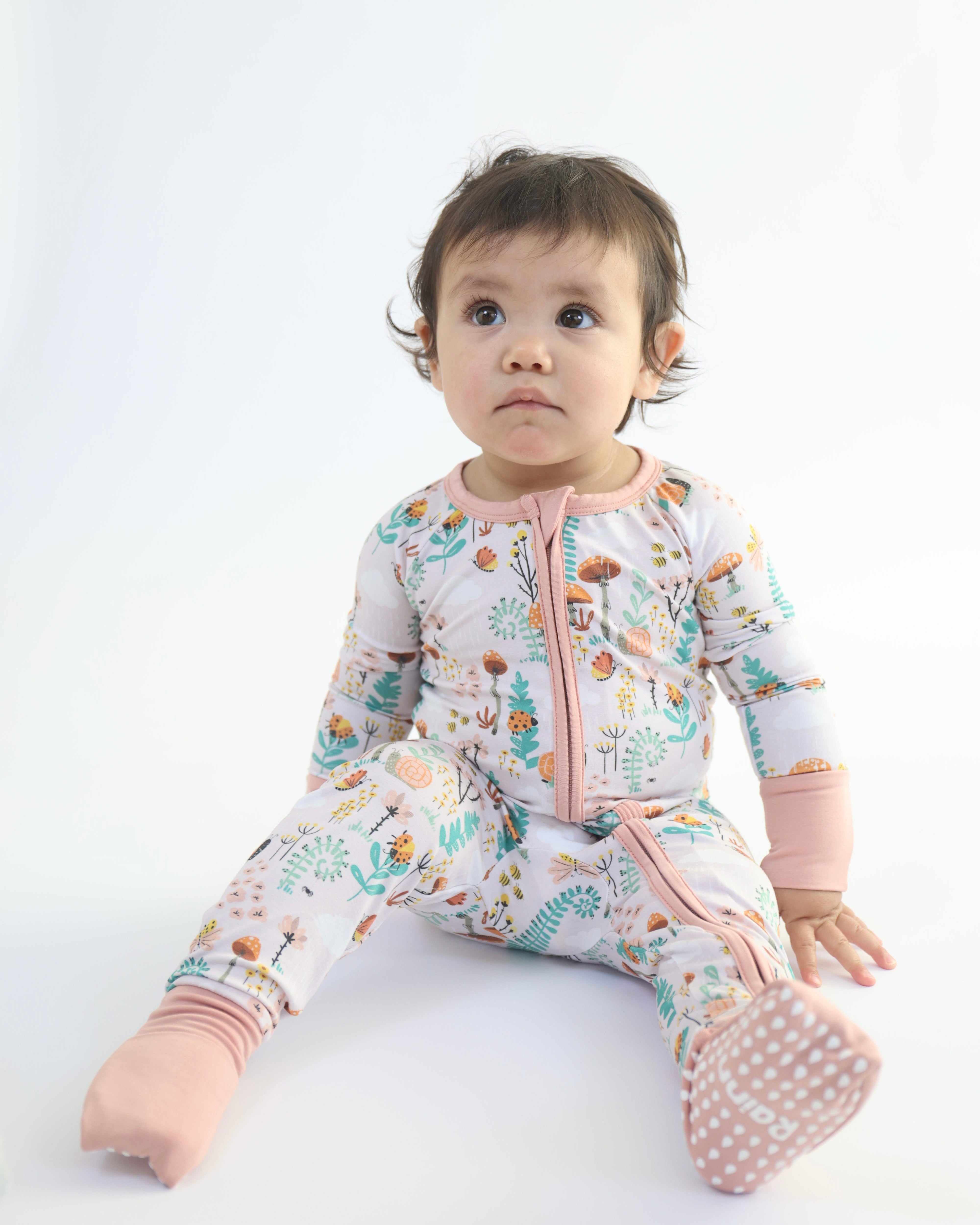 Little one in Fern Zipp Jammies by Rainn, featuring a lively floral print and comfy two-way zipper.