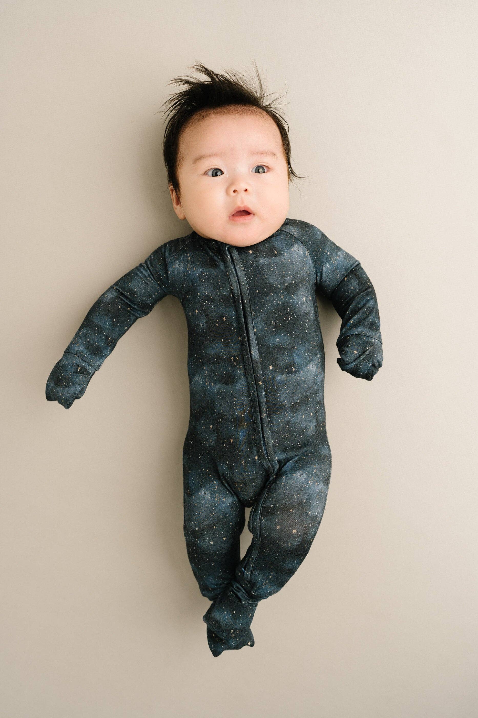 Adorable baby in Moonlight Bamboo Sleeper by Little One Shop, 6-12M, featuring stars design for ultimate comfort and softness.