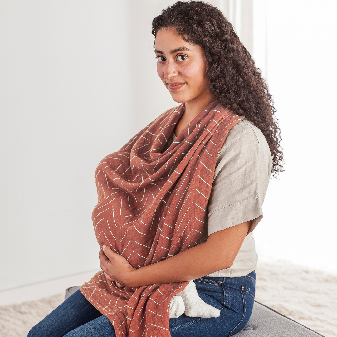 Mom using Itzy Ritzy Breastfeeding Boss™ as a nursing cover, showcasing its soft cotton muslin design for comfort.