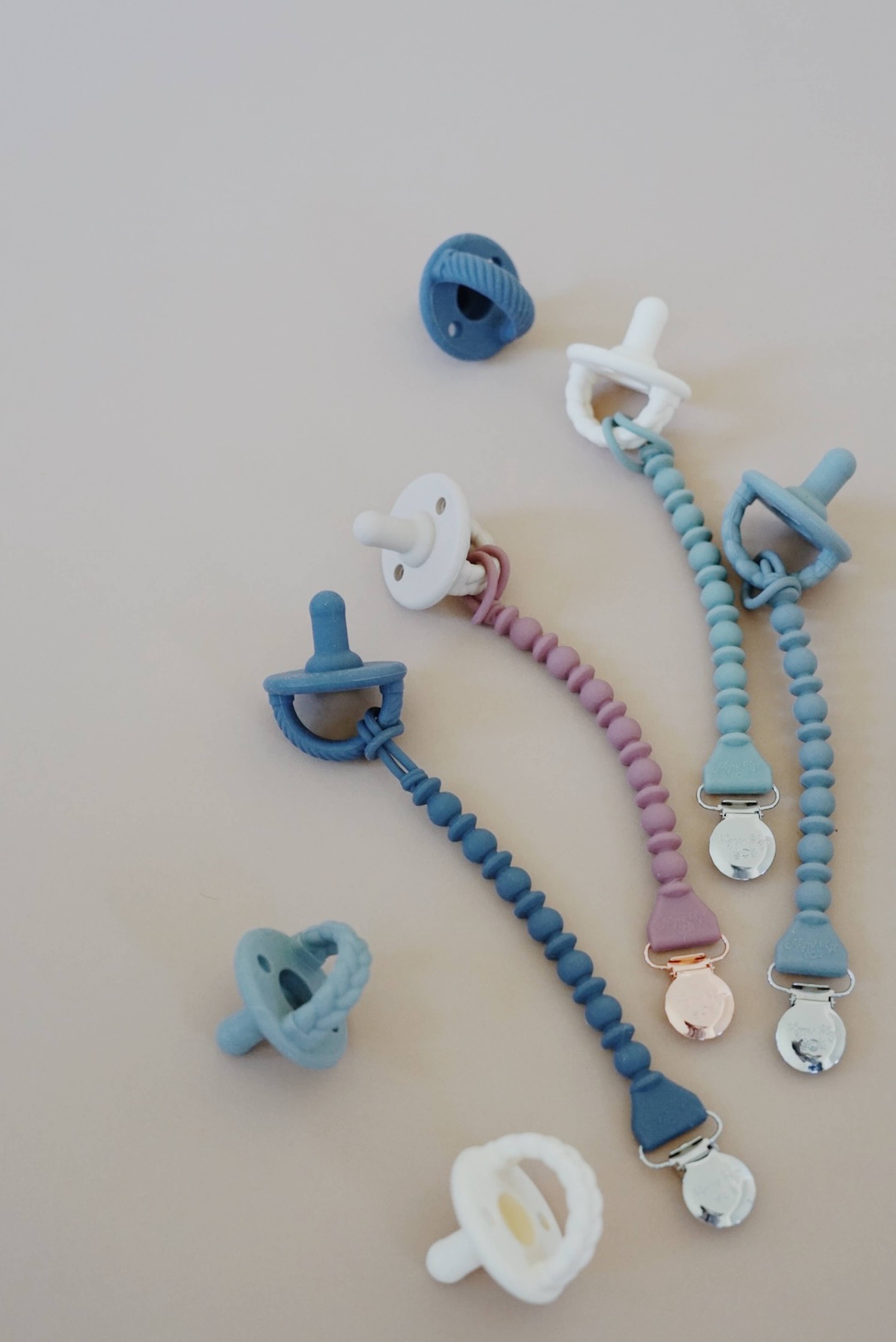 Colorful Sweetie Strap™ silicone pacifier clips in various styles, perfect for keeping pacifiers secure and stylish.