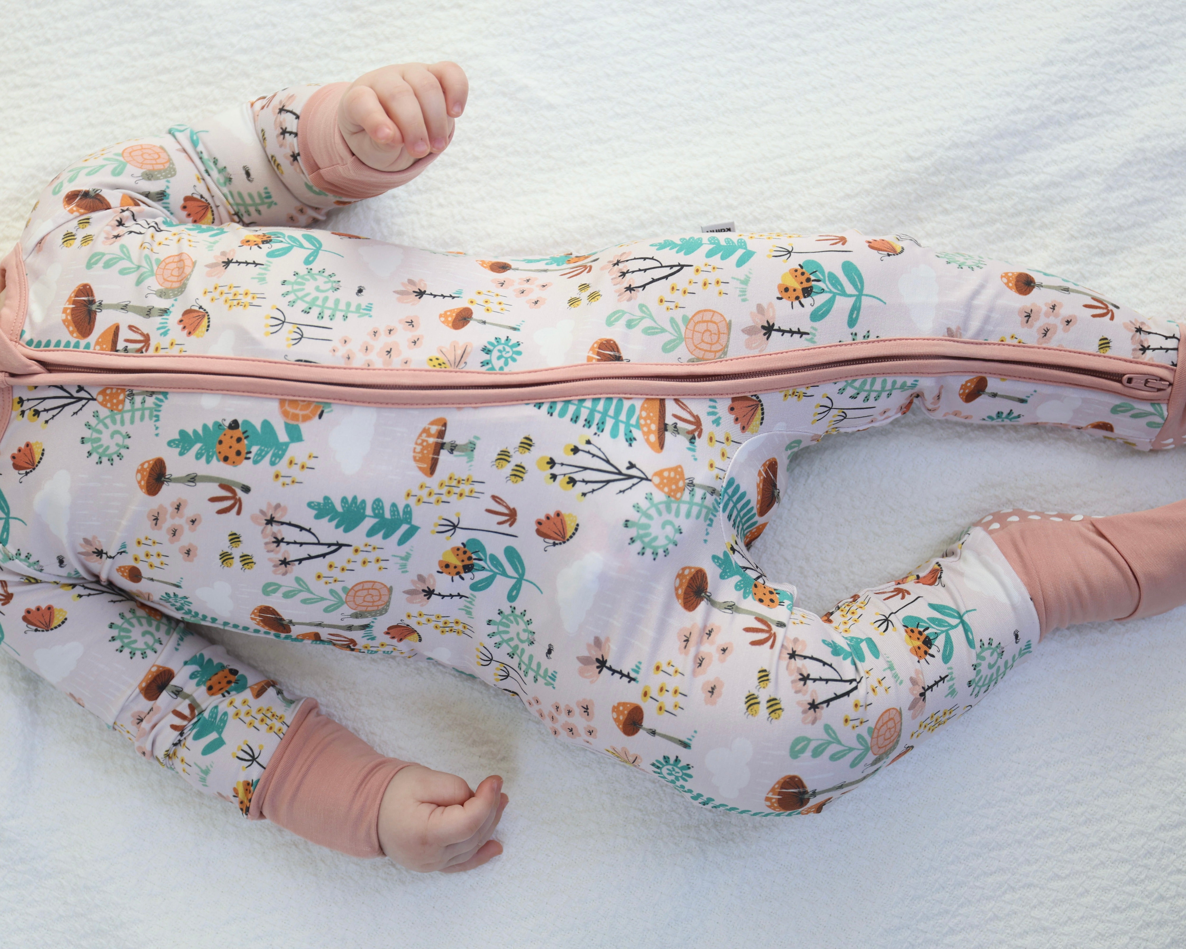 Baby in Fern Zipp Jammies by Rainn, featuring cute floral print and convenient two-way zipper for easy diaper changes.