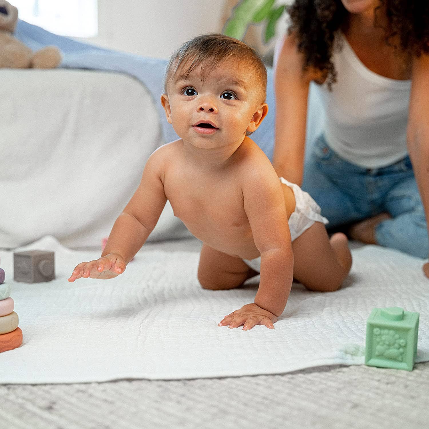 Baby exploring on a soft blanket with toys nearby, enjoying playtime in a cozy environment.