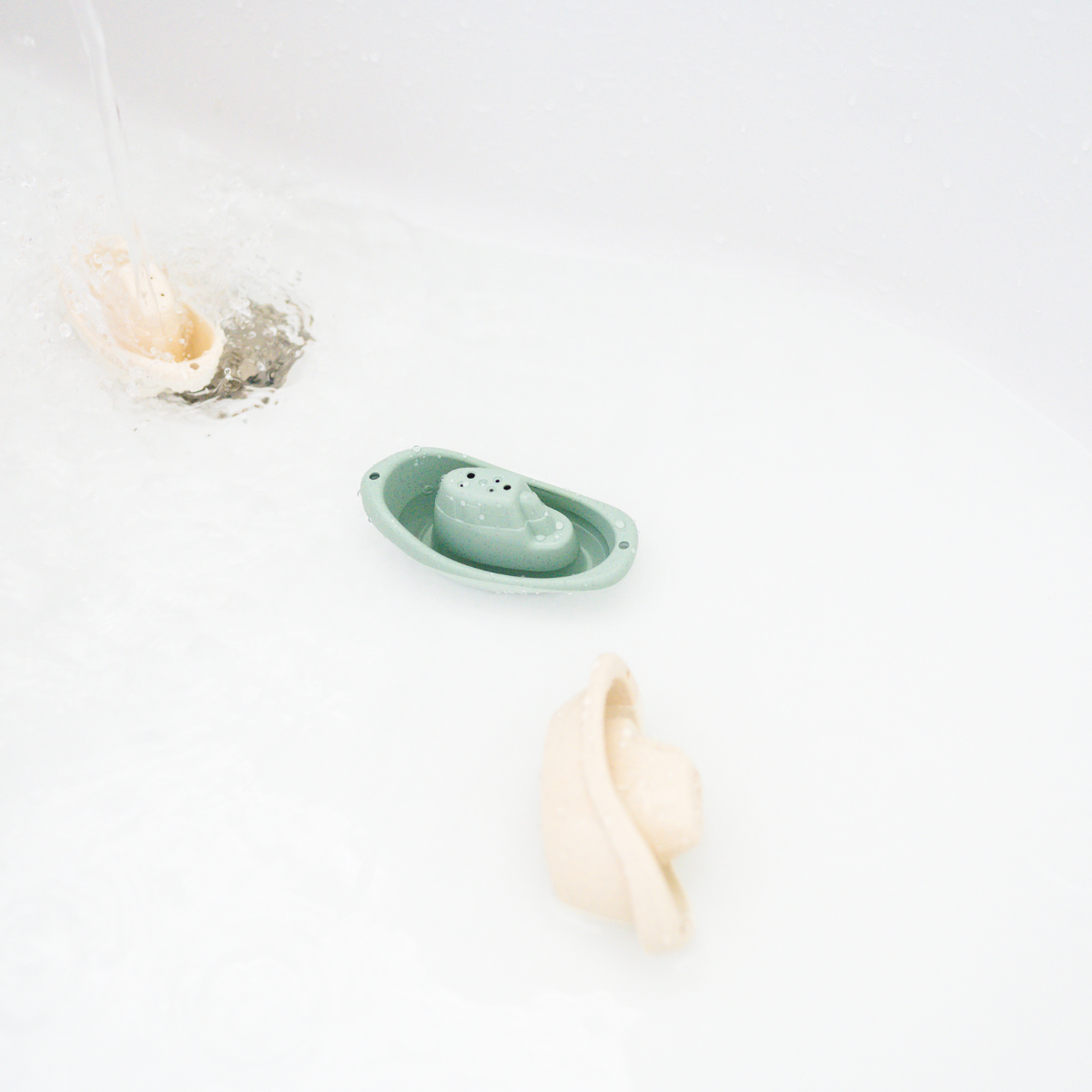 Eco-friendly wheat straw toy boats floating in a bathtub, part of Bug + Bean Kids sustainable play set for imaginative water fun.