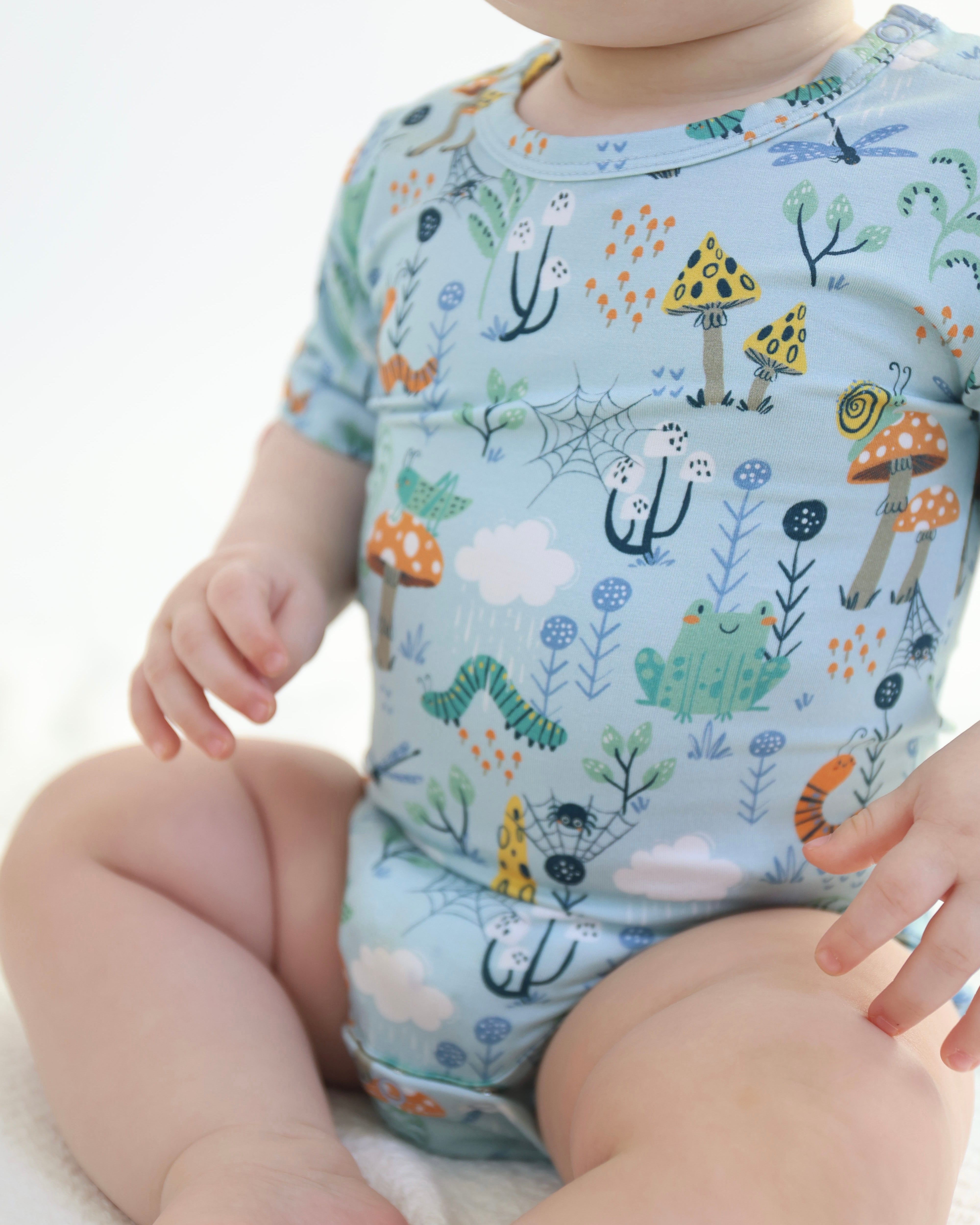 Adorable baby in Critter Hollow bamboo bodysuit featuring colorful animal print, perfect for sensitive skin and cozy comfort.