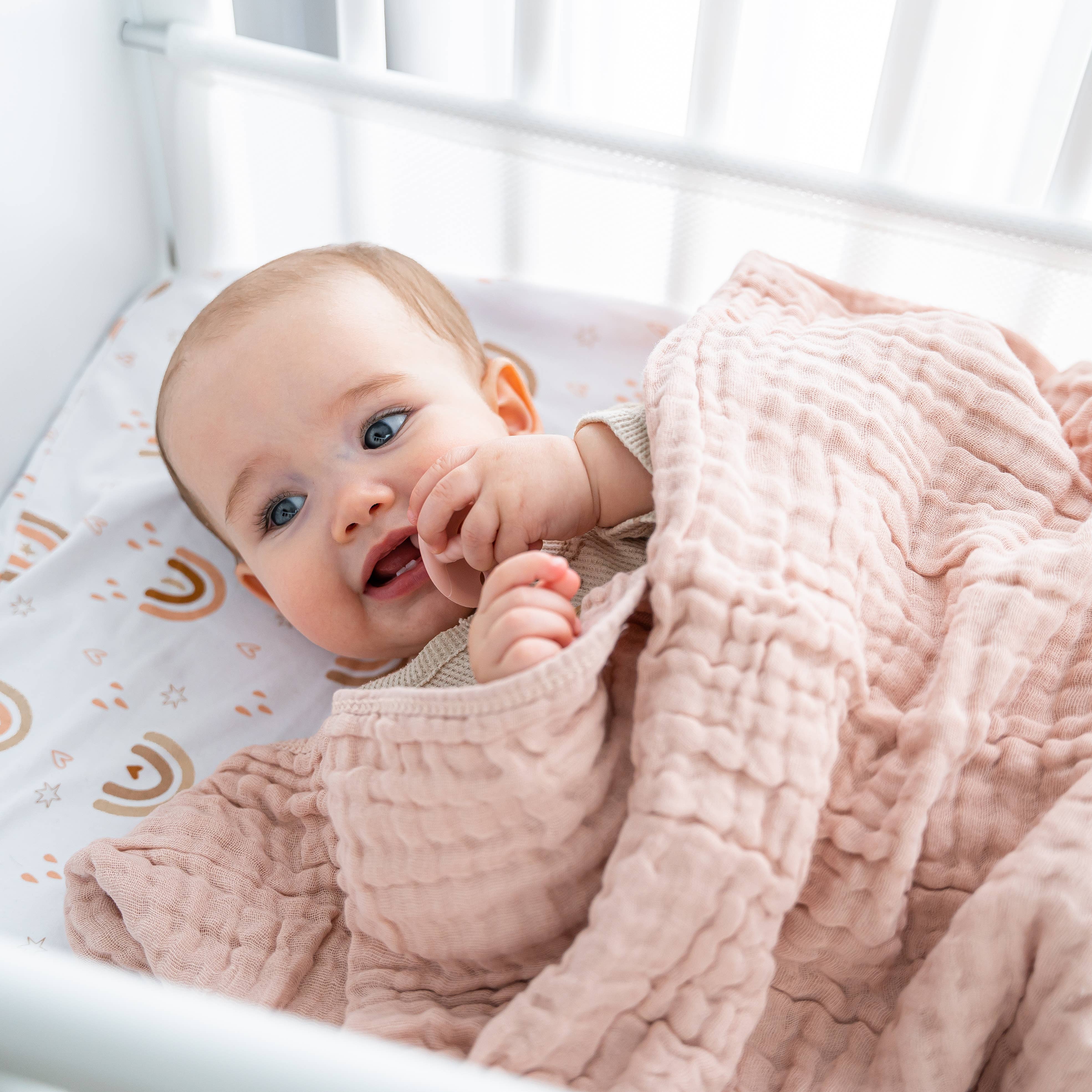 Happy baby snuggled in soft Comfy-Cubs muslin cotton blanket, enjoying cozy comfort and gentle warmth.