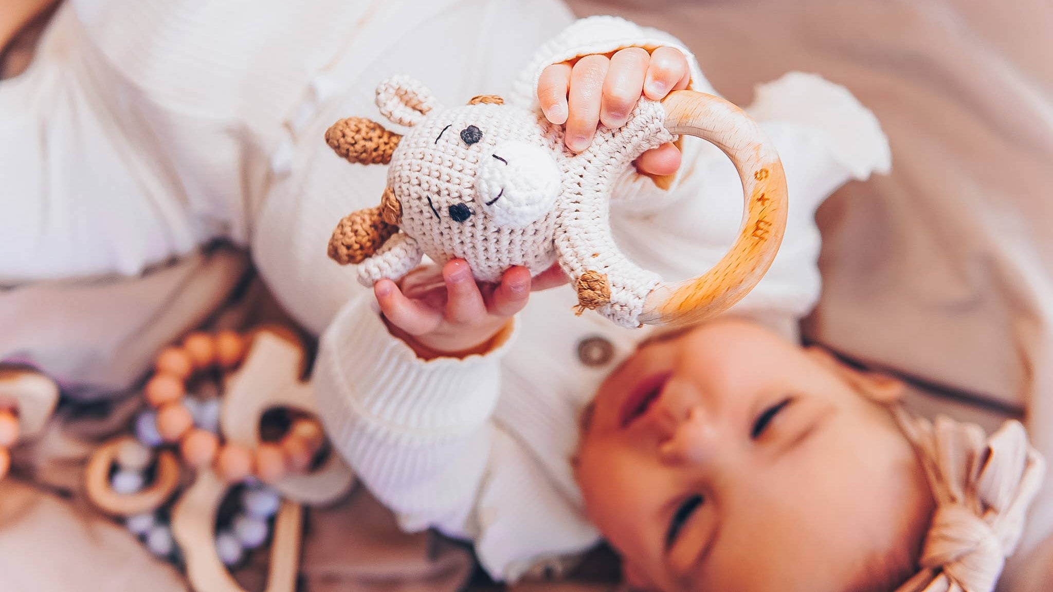Baby enjoying a giraffe handmade crochet rattle by Marlowe and Sage, perfect for sensory play and early development.