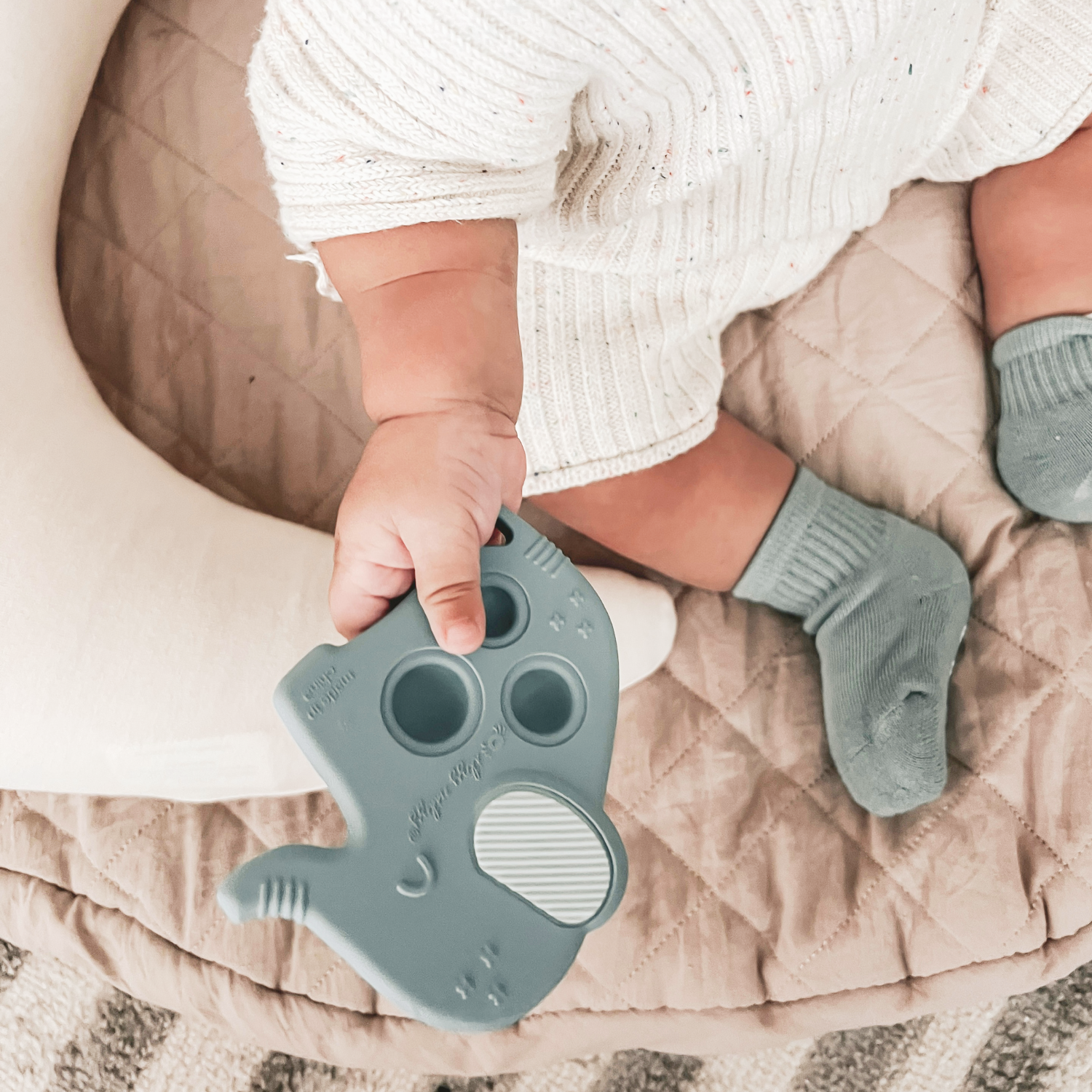 Baby using Itzy Ritzy Itzy Pop Elephant Sensory Toy for soothing teething relief, featuring fun popping sounds and eco-friendly design.