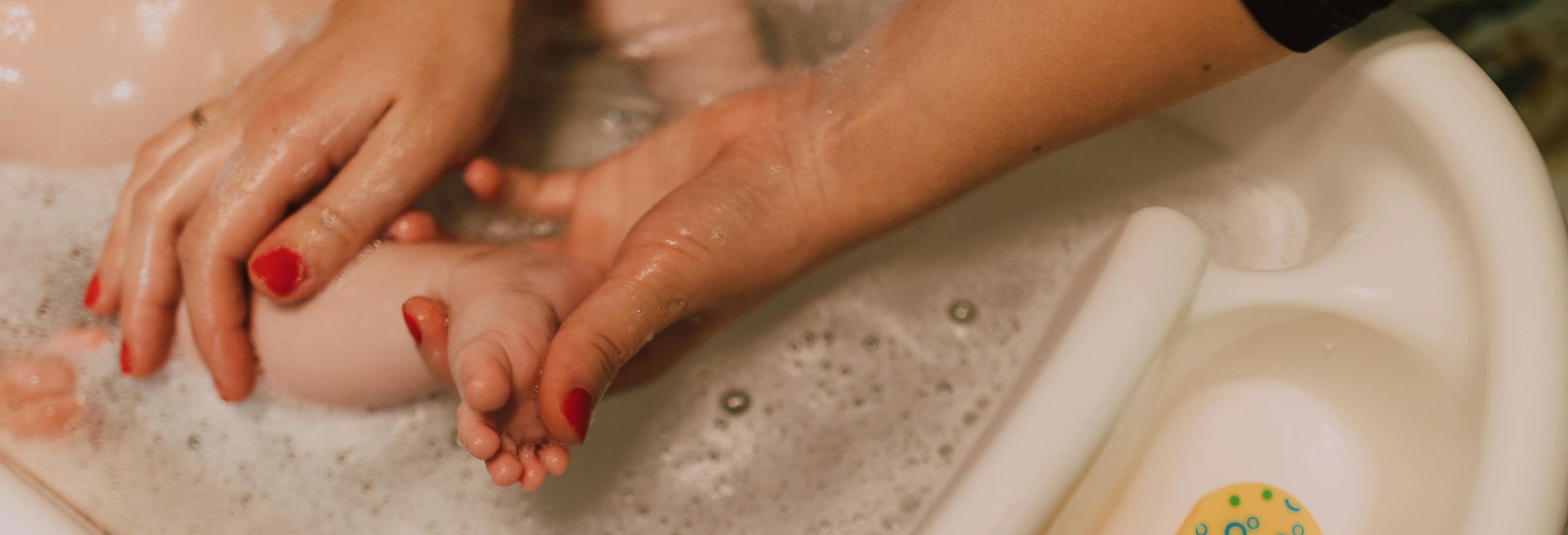 A loving parent gently washing a baby's feet in a bubbly bath, showcasing tender bonding moments.